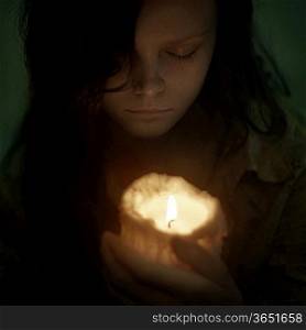 portrait of a beautiful woman with a candle on a black background
