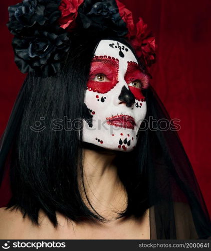 portrait of a beautiful woman with a sugar skull makeup with a wreath of flowers on her head, red background