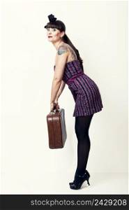 Portrait of a beautiful woman with a vintage look posing with a suitcase
