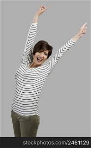 Portrait of a beautiful woman with arms on teh air, over a gray background