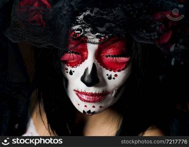 portrait of a beautiful woman with closed eyes and a sugar skull makeup with a wreath of flowers on her head, close up