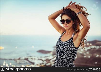 Portrait of a beautiful woman with curly hair on the beach, attractive gorgeous model over sea background, summertime fashionable look 
