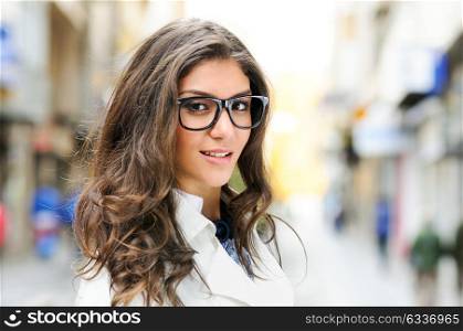 Portrait of a beautiful woman with eye glasses smiling in urban background