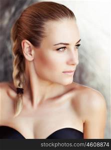 Portrait of a beautiful woman with natural makeup and stylish braid hairstyle looking aside, authentic beauty, fashion look of a gorgeous young model with perfect skin
