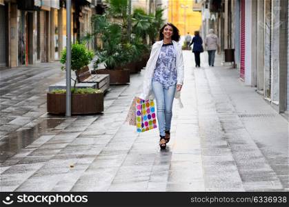 Portrait of a beautiful woman with shopping bags walking along a commercial street
