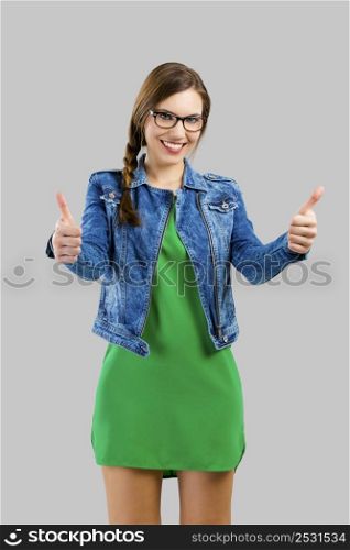 Portrait of a beautiful woman with thumbs up, isolated over grey background