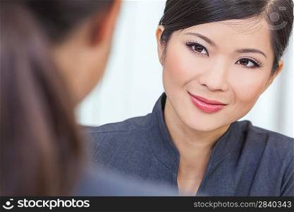 Portrait of a beautiful young Asian Chinese woman or businesswoman in office meeting with female colleague