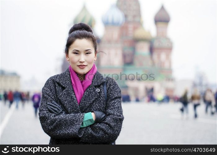 Portrait of a beautiful young asian woman in a gray coat on a red square, Moscow Russia