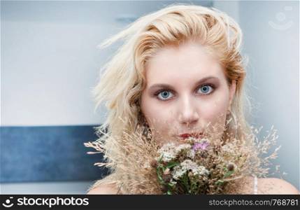 portrait of a beautiful young blonde woman with a bouquet of flowers