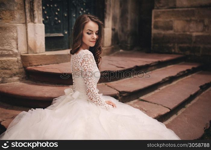 portrait of a beautiful young bride in a white wedding dress with long hair in the old European city. Woman near old building. wedding day.. portrait of a beautiful young bride in a white wedding dress with long hair in the old European city. Woman near old building. wedding day