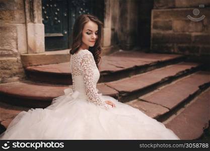 portrait of a beautiful young bride in a white wedding dress with long hair in the old European city. Woman near old building. wedding day.. portrait of a beautiful young bride in a white wedding dress with long hair in the old European city. Woman near old building. wedding day