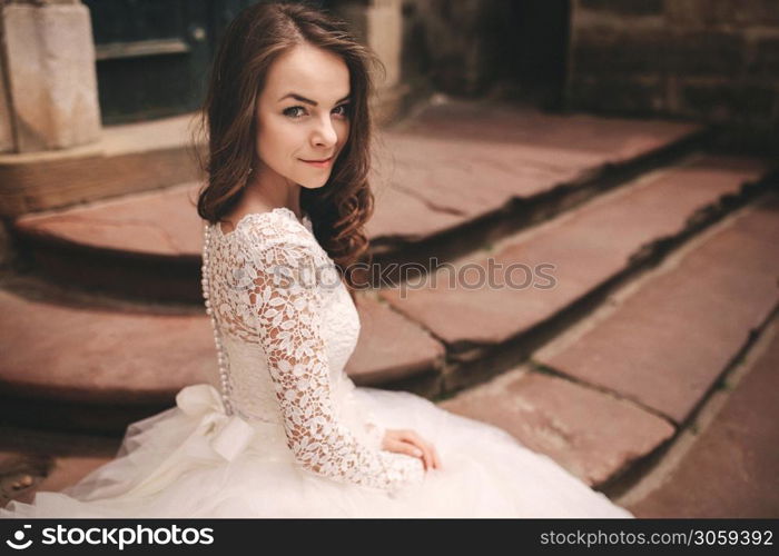 portrait of a beautiful young bride in a white wedding dress with long hair in the old European city. Woman near old building. wedding day.. portrait of a beautiful young bride in a white wedding dress with long hair in the old European city. Woman near old building. wedding day