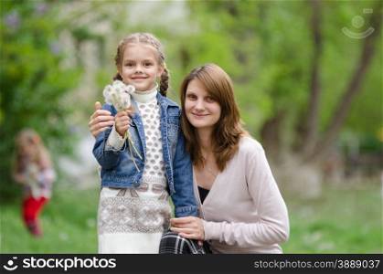 portrait of a beautiful young girl and the daughter of European type, with a bouquet of dandelions