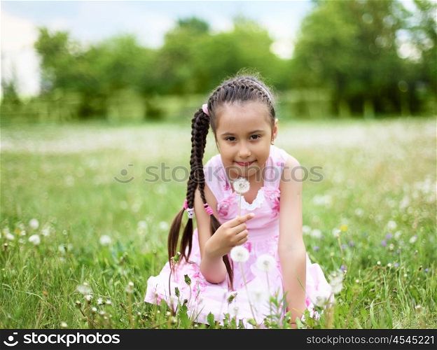 Portrait of a beautiful young girl on a green meadow.