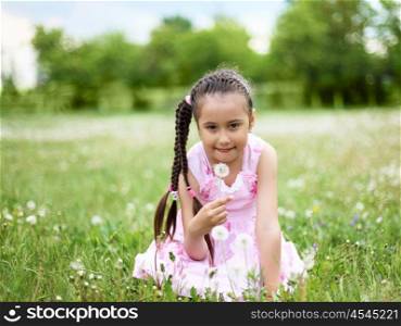 Portrait of a beautiful young girl on a green meadow.