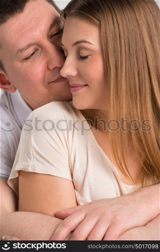 Portrait of a beautiful young happy smiling couple embracing at home while sitting on sofa