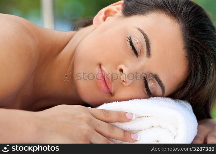 Portrait of a beautiful young Latina Hispanic woman eyes closed and smiling while relaxing outside at a health spa