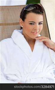 Portrait of a beautiful young Latina Hispanic woman smiling in a white bathrobe outside at a health spa