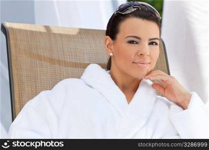 Portrait of a beautiful young Latina Hispanic woman smiling in a white bathrobe outside at a health spa