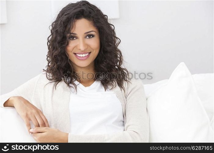 Portrait of a beautiful young Latina Hispanic woman smiling with perfect teeth sitting on a white sofa