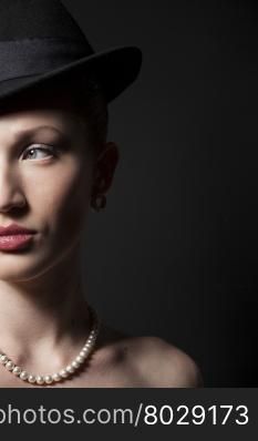 Portrait of a beautiful young model in black hat on black background