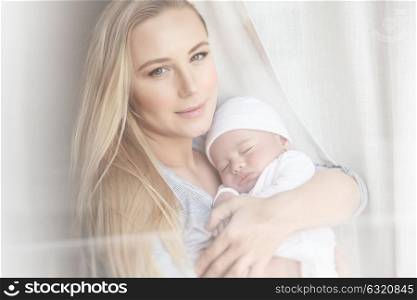 Portrait of a beautiful young mother holding her little precious baby, enjoying parenthood at home, child care and love concept