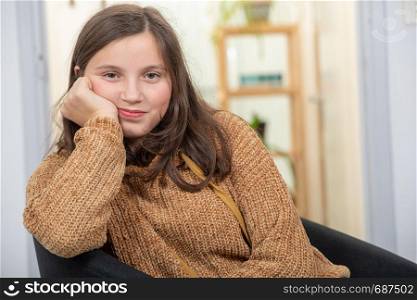 portrait of a beautiful young teenager girl sitting on armchair