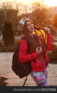 Portrait of a beautiful young traveler woman with a backpack, bright orange sunset light, traveling along Europe, freedom and active lifestyle concept