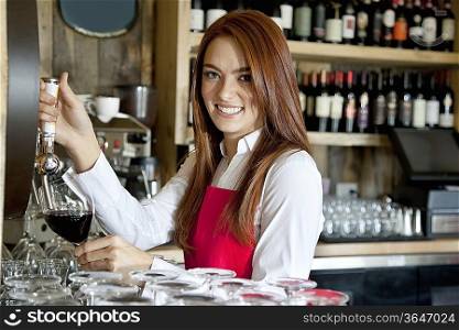 Portrait of a beautiful young waitress removing wine in bar