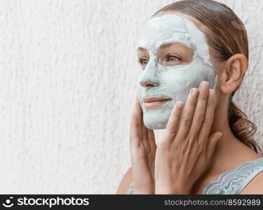 Portrait of a Beautiful Young Woman Applying Clay Mask Isolated on White Background. Enjoying Day Spa in Luxury Beauty Salon.. Skin Care Concept