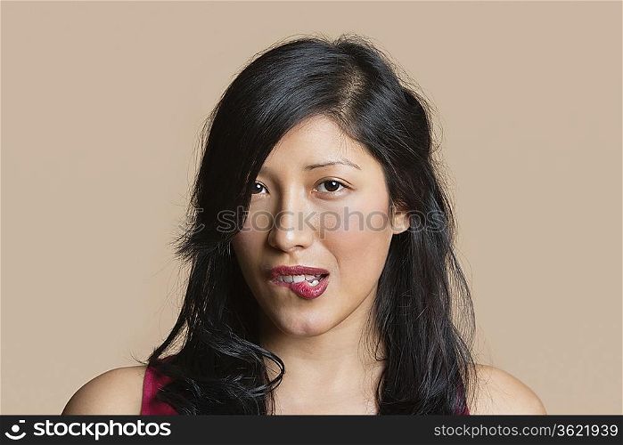 Portrait of a beautiful young woman biting lip over colored background