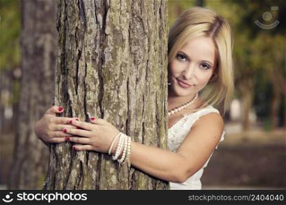Portrait of a beautiful young woman embracing a tree
