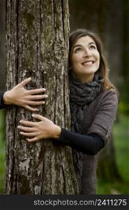 Portrait of a beautiful young woman hugging a tree in fall season