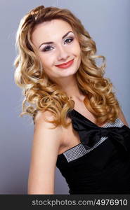 Portrait of a beautiful young woman in black dress with curly hair