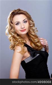 Portrait of a beautiful young woman in black dress with curly hair