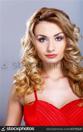 Portrait of a beautiful young woman in red dress with curly hair