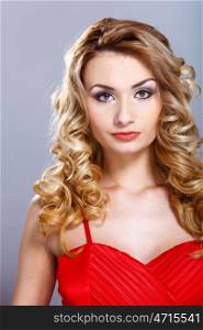 Portrait of a beautiful young woman in red dress with curly hair