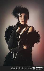Portrait of a beautiful young woman in style of the great Gatsby of the 20s. Vintage clothing and jewelry. Portrait of beautiful woman in boa from ostrich feathers and pearls beads. 20&rsquo;s years.
