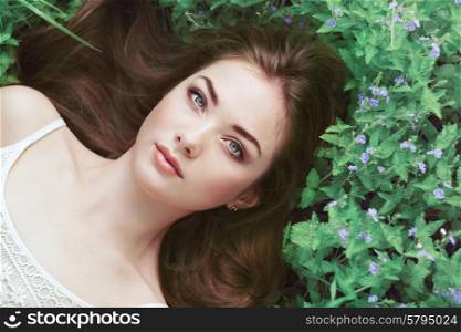 Portrait of a beautiful young woman in summer garden. Girl on nature. Spring flowers. Fashion beauty