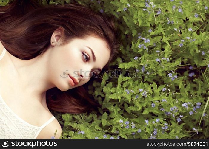 Portrait of a beautiful young woman in summer garden. Girl on nature. Spring flowers. Fashion beauty