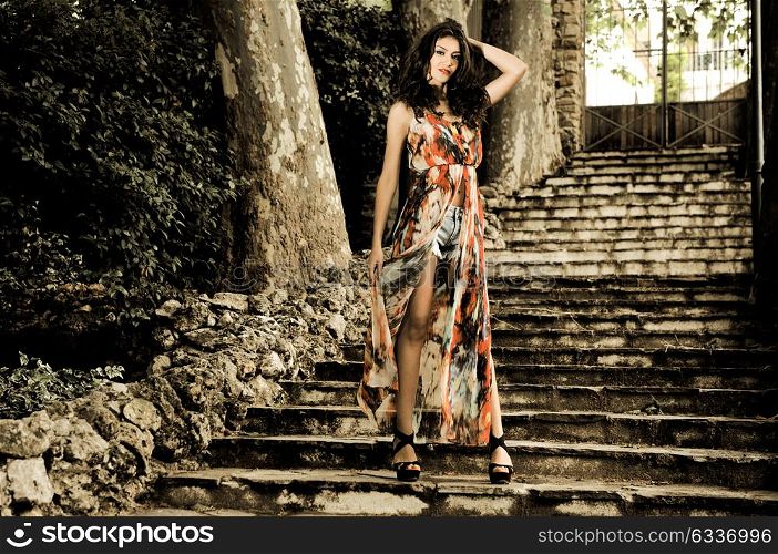 Portrait of a beautiful young woman, model of fashion, in a garden stairs