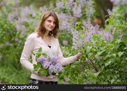 portrait of a beautiful young woman of the European type, with a bouquet of lilac in the hands of