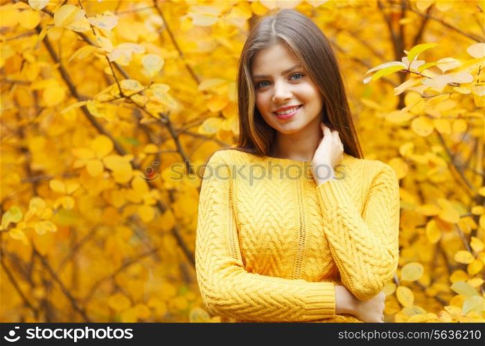 Portrait of a beautiful young woman over autumn tree background