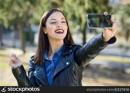Portrait of a beautiful young woman selfie in the park with a smart phone