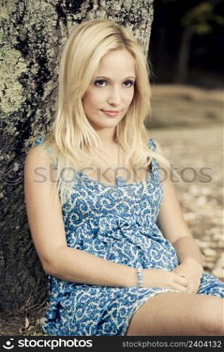 Portrait of a beautiful young woman sitting close to a tree
