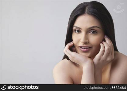 Portrait of a beautiful young woman touching her face over colored background