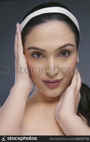 Portrait of a beautiful young woman touching her face over colored background