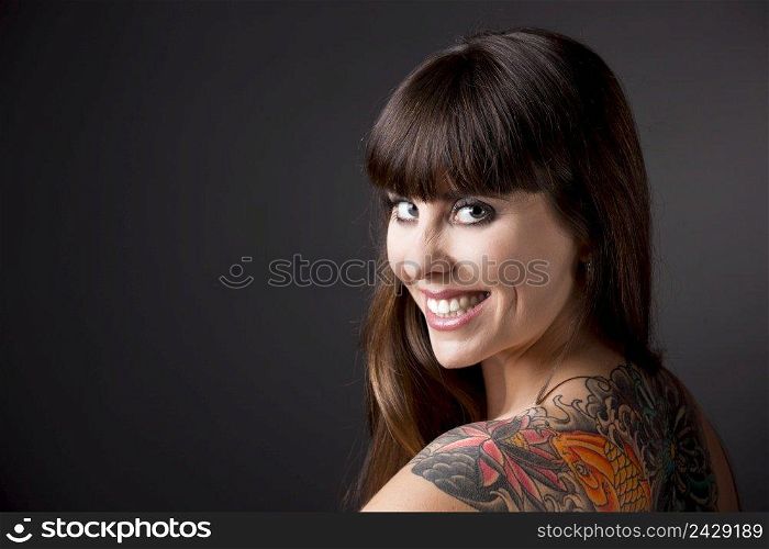 Portrait of a beautiful young woman with a tattoo on the backs