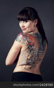 Portrait of a beautiful young woman with a tattoo on the backs