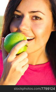 portrait of a beautiful young woman with apple outdoor